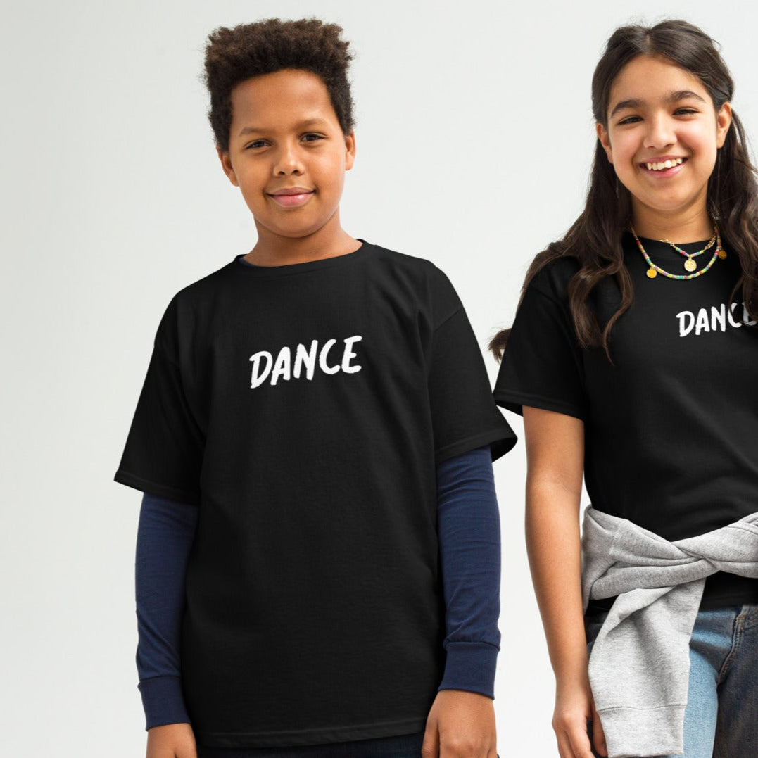 Two children standing and posing in a studio setting, one wearing a black t-shirt with the word 'Dance' printed on the front, the other wearing a grey sweatshirt with a hood.