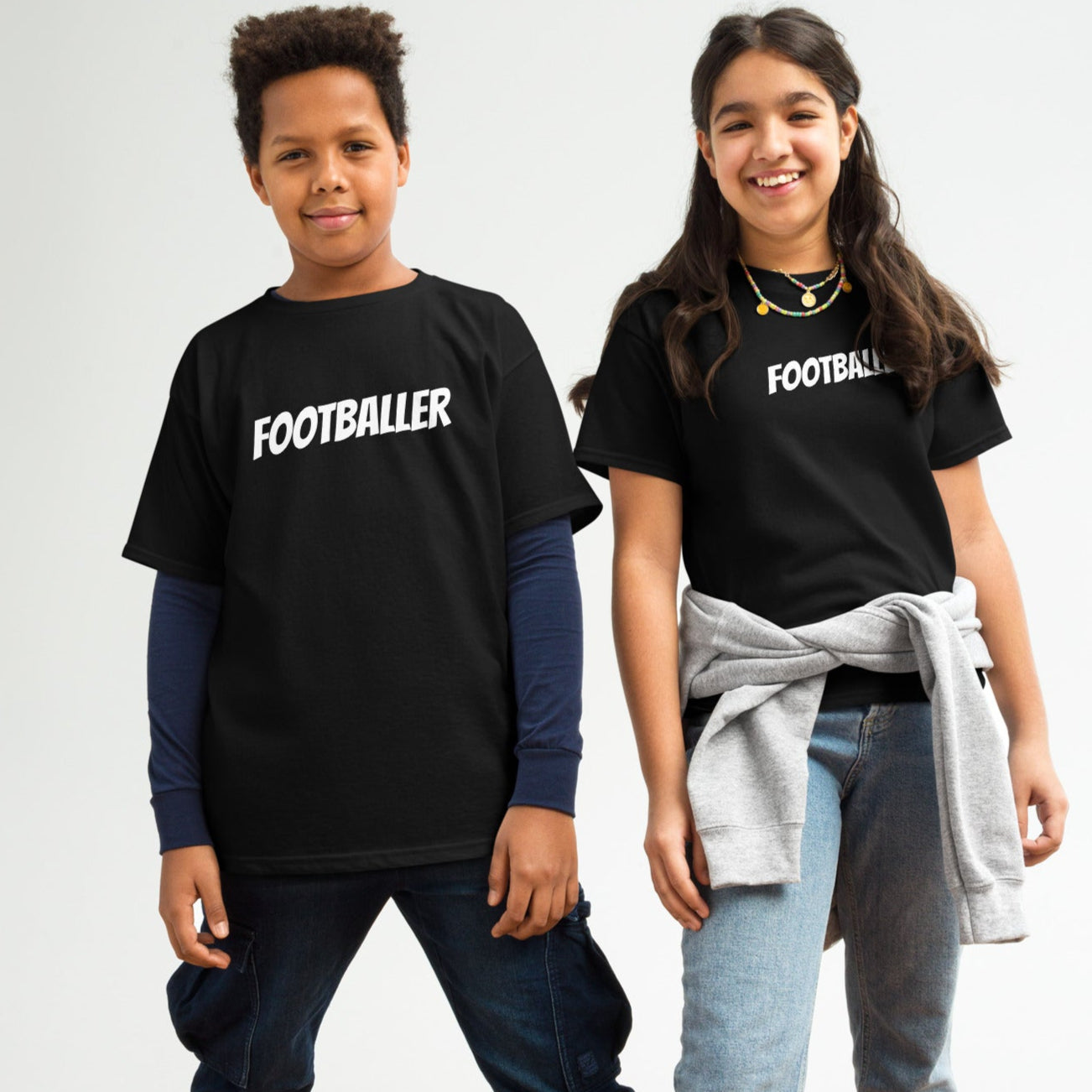 Two young people, one male and one female, wearing black crew neck T-shirts with the word 'FOOTBALLER' printed on the front.