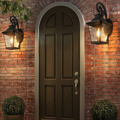 Dark wooden door with wall-mounted lanterns on a brick wall