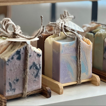 Handmade soap bars in various colors on wooden stands with decorative string