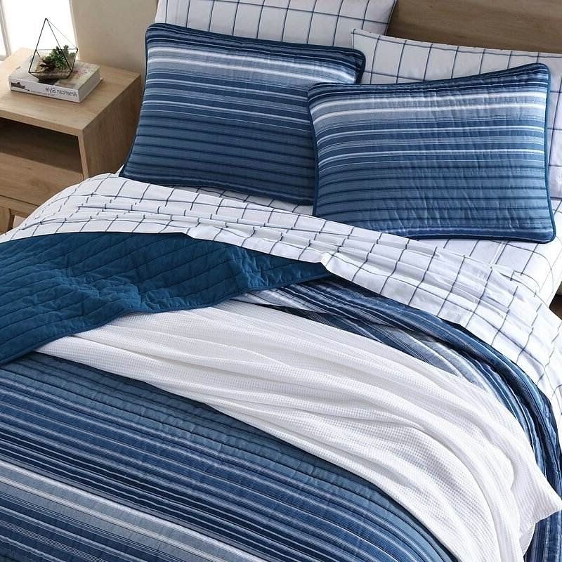 Blue and white striped bedding set on a bed with a wooden nightstand.