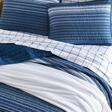 Blue and white striped bedding set on a bed with a wooden nightstand.