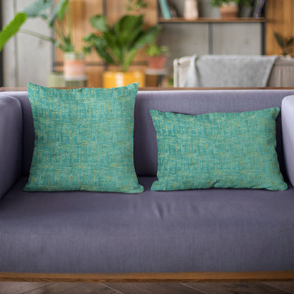 Two green textured pillows on a gray sofa with a blurred indoor background