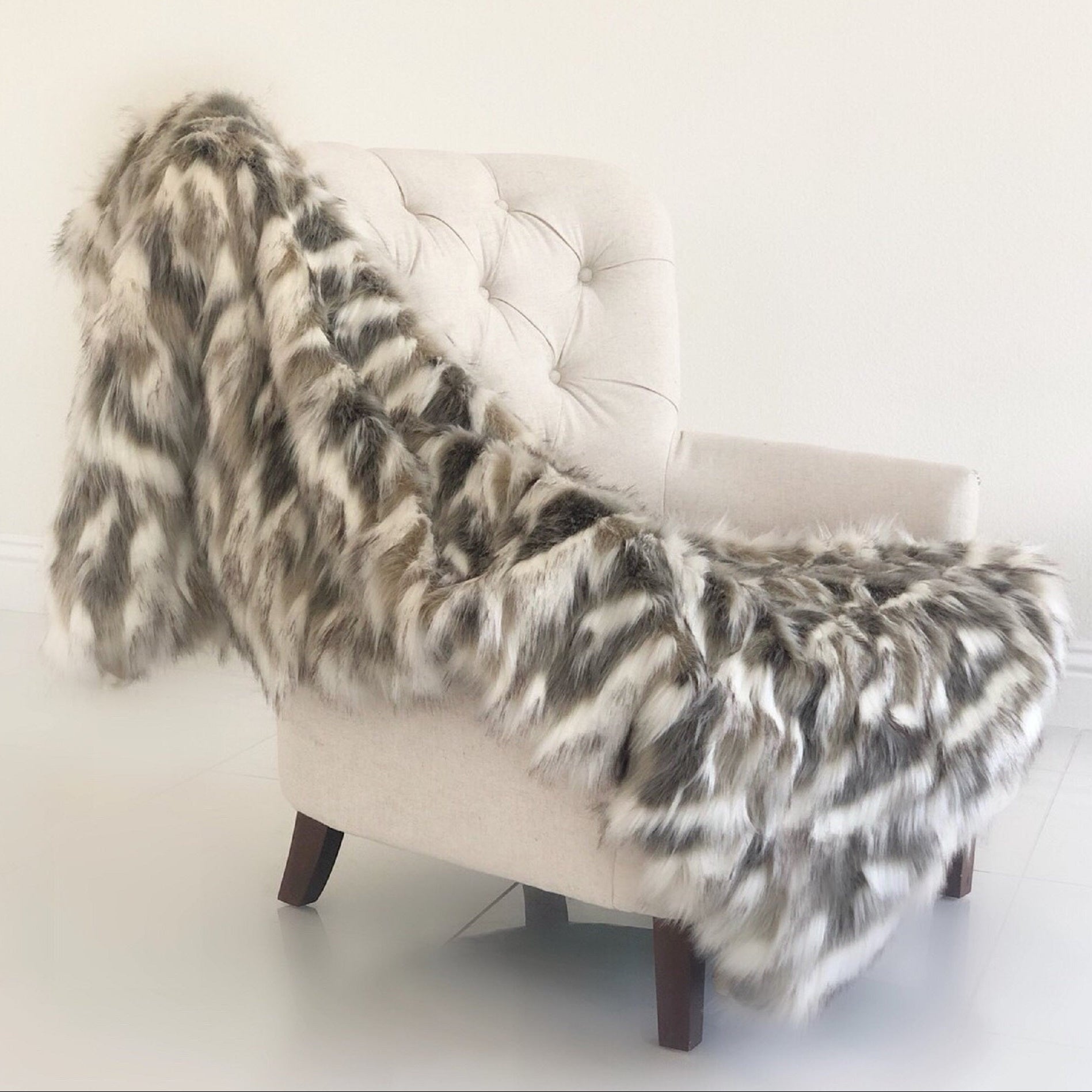 White chair with a fur throw draped over it against a white background