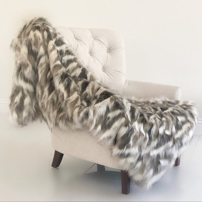 White chair with a fur throw draped over it against a white background