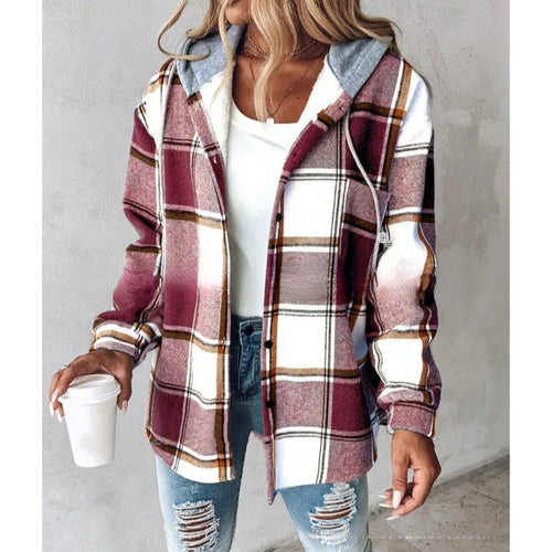 Person wearing a plaid shirt over a white top and ripped jeans, holding a coffee cup.