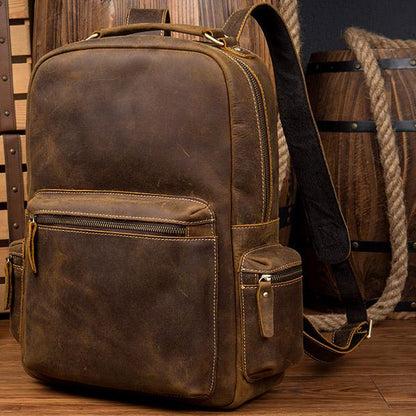 Brown leather backpack with visible stitching on a wooden surface.