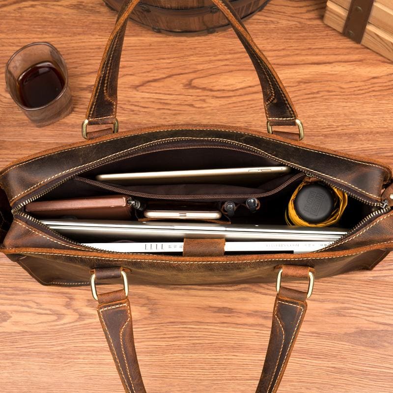 Brown leather briefcase with laptop on a wooden surface