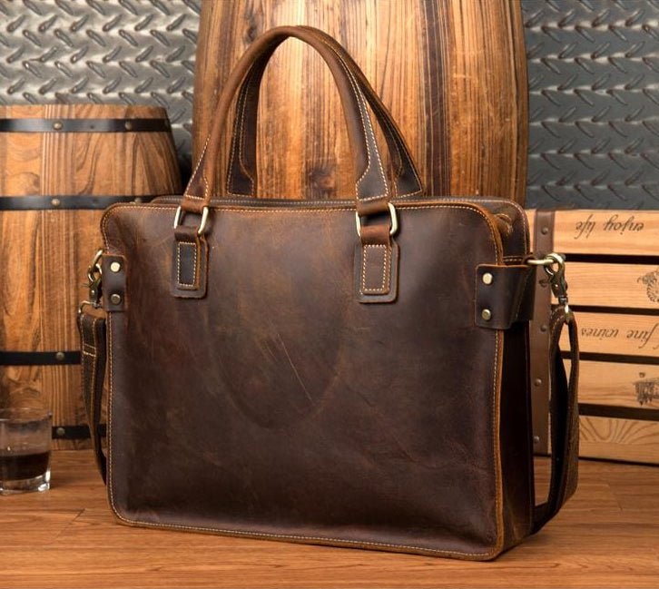 Brown leather briefcase on a wooden surface with barrels and crates in the background