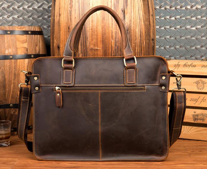 Brown leather briefcase on a wooden surface with barrels in the background