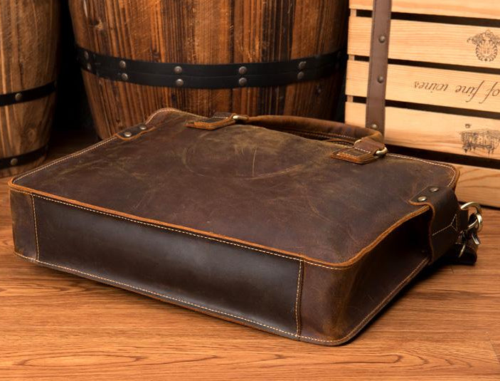 Brown leather bag on a wooden surface with barrels in the background